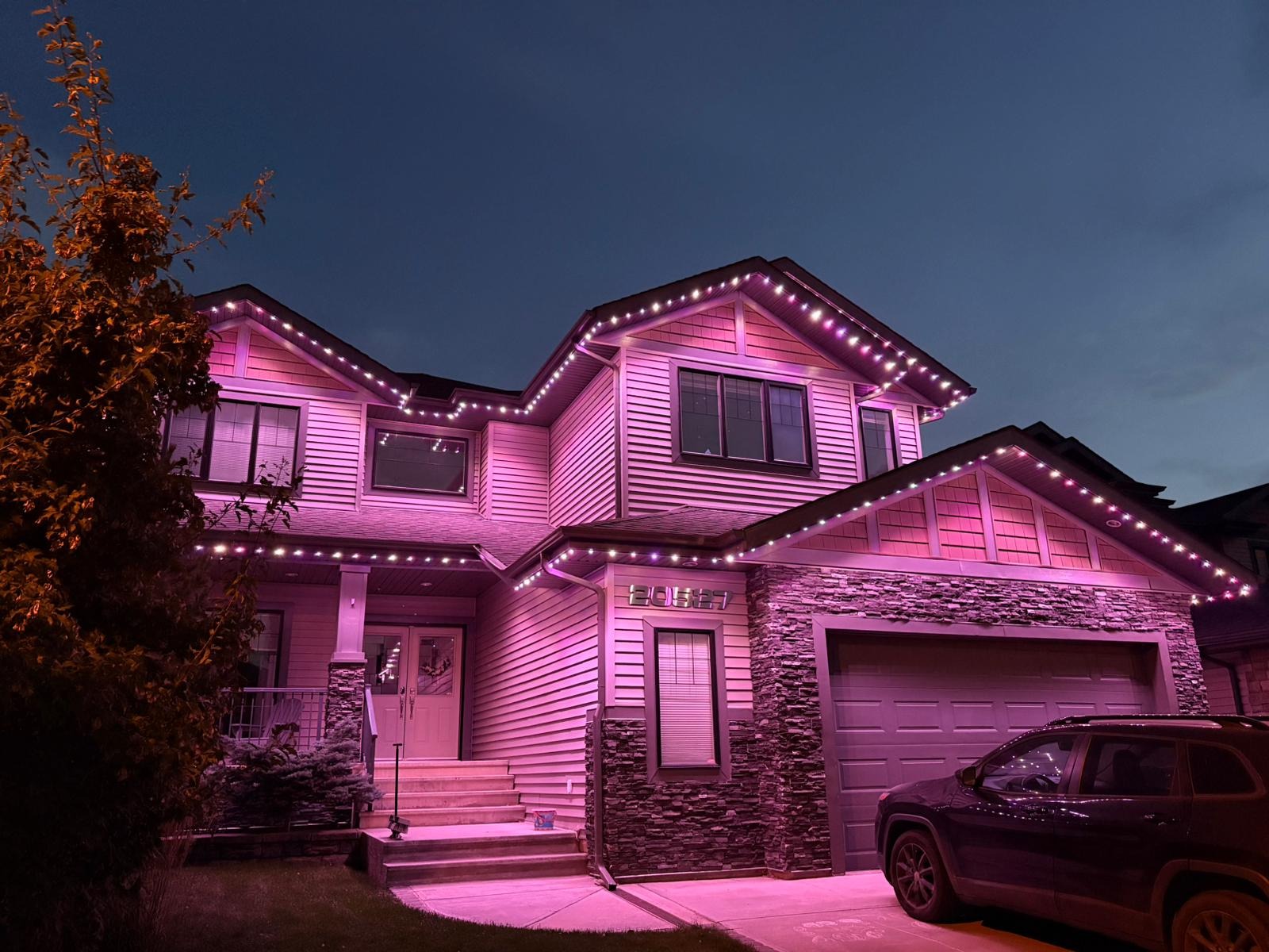 Two-story home washed in soft pink permanent lighting