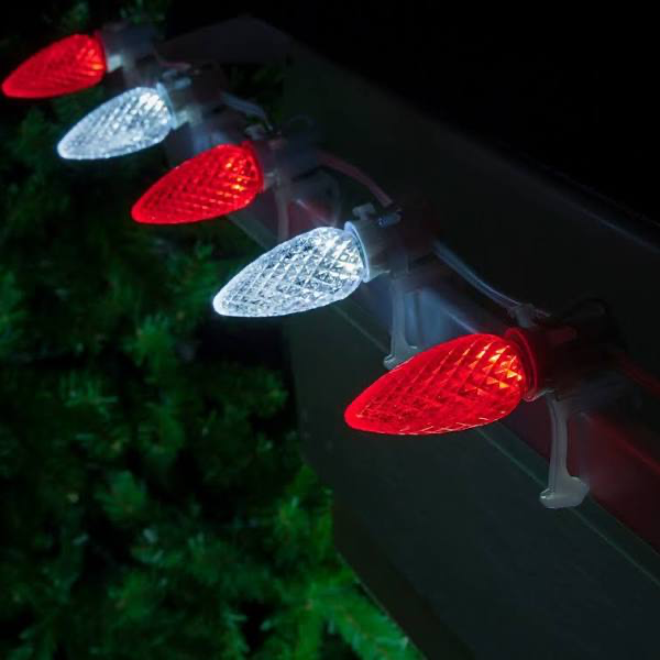 Close-up of red and white C9 bulbs mounted to a gutter edge with white clips